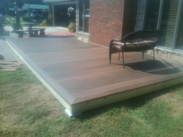 New wood deck and wicker chair beside a brick house in Tigerton