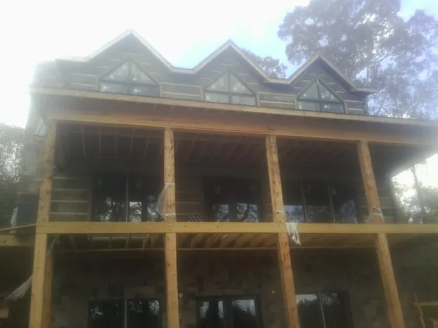 Dormers and porch framing on a large log home under construction — Roof Coating work by our crew in Tigerton