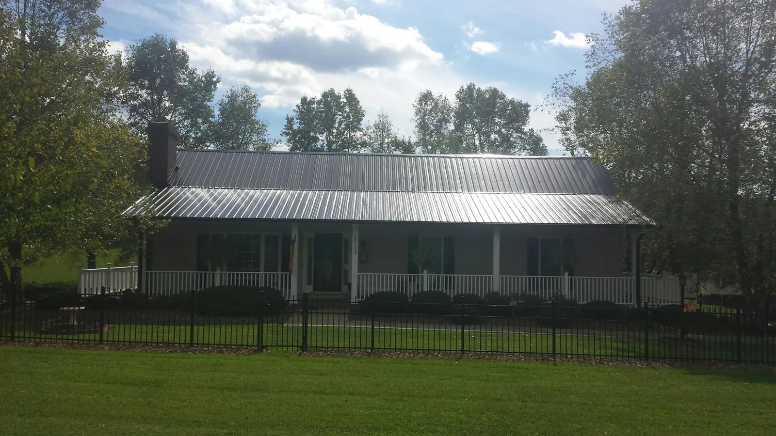 Gray metal roof on a brick ranch with a full width front porch — Gutter Guard Installation work by our crew in Tigerton