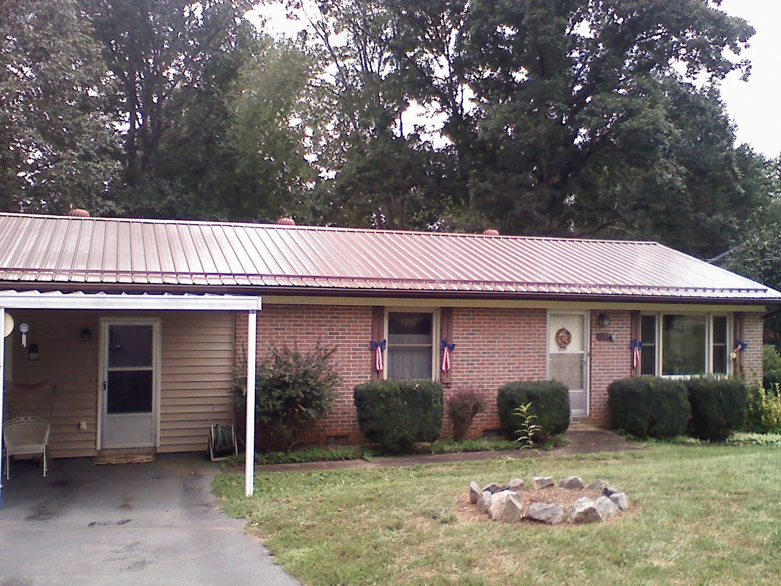 Bronze metal roof and carport on a brick ranch home — Roof Repair work by our crew in Tigerton