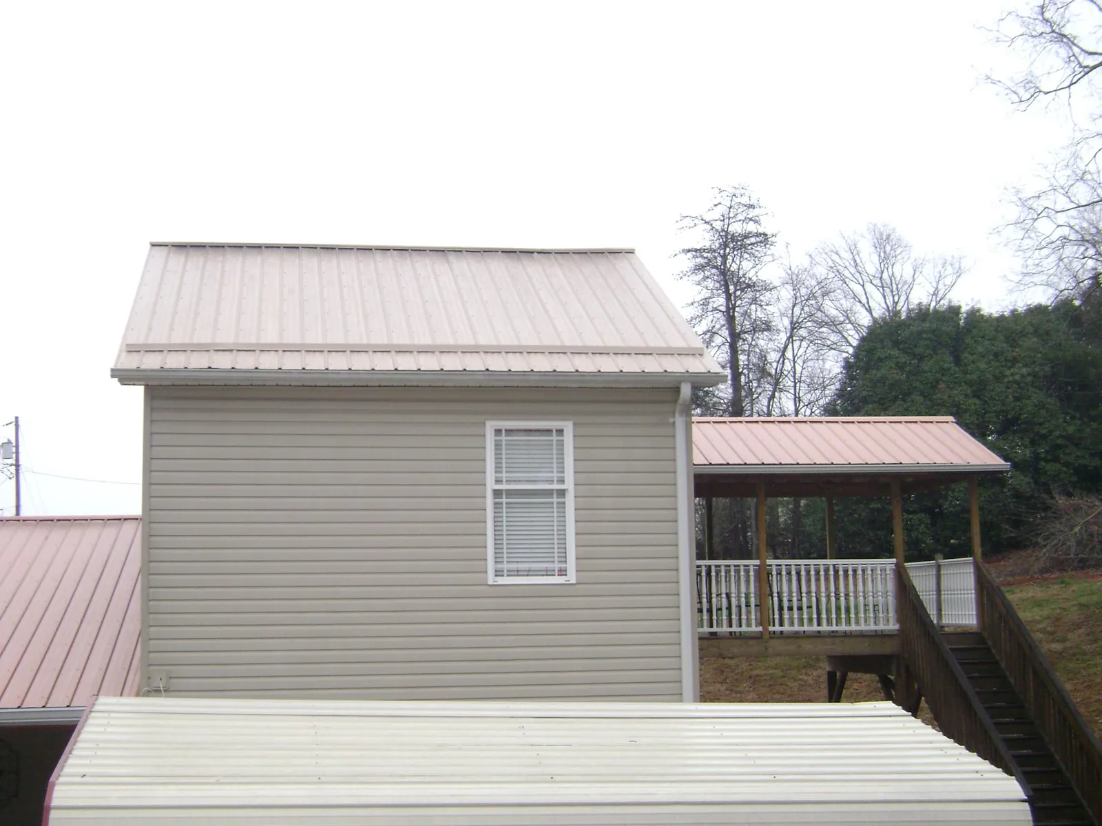 Tan metal roofs on a two story addition and attached porch, from a Roof Replacement job in Tigerton
