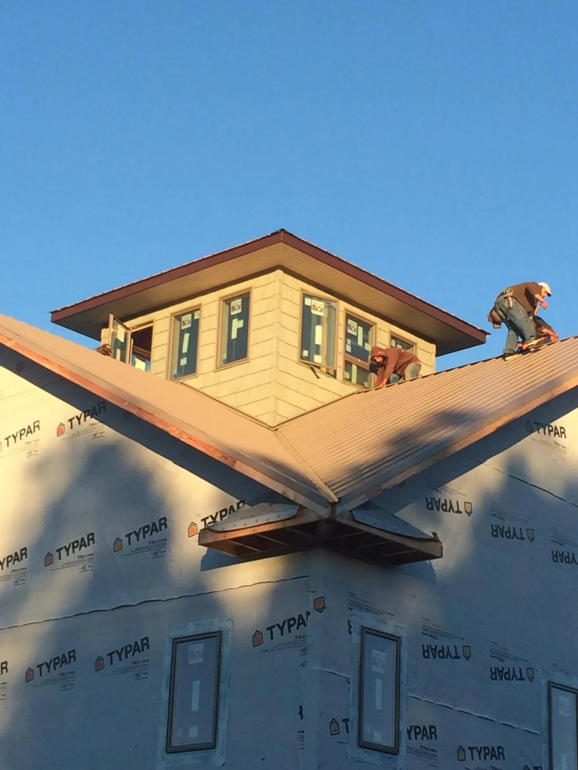 Roofers working around a rooftop cupola on a new metal roof at sunset — Roof Waterproofing in Tigerton by Roofing Brothers